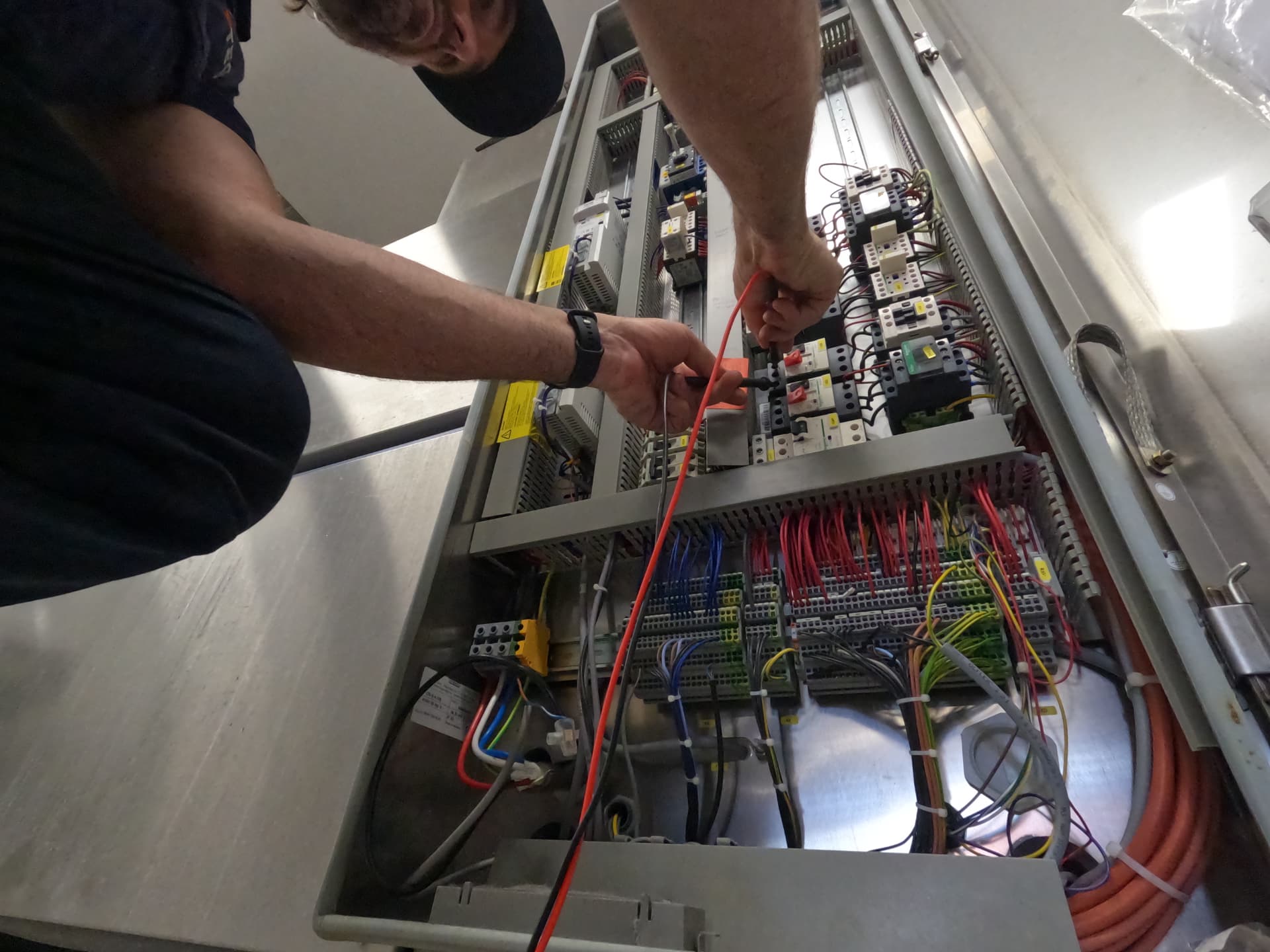 CHEFTECH technician testing circuit breakers and control wiring inside a commercial equipment electrical cabinet